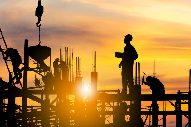 Silhouette of Engineer and worker on building site, construction site at sunset in evening time